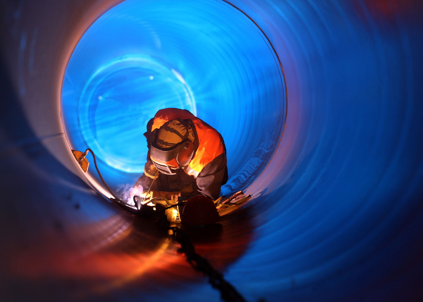 sevgen_45809_Blog_2025_4-April Welder working inside a pipe wearing protective gear with sparks flying.